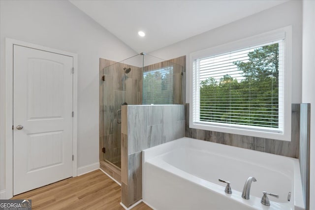 bathroom with a stall shower, a garden tub, wood finished floors, and vaulted ceiling