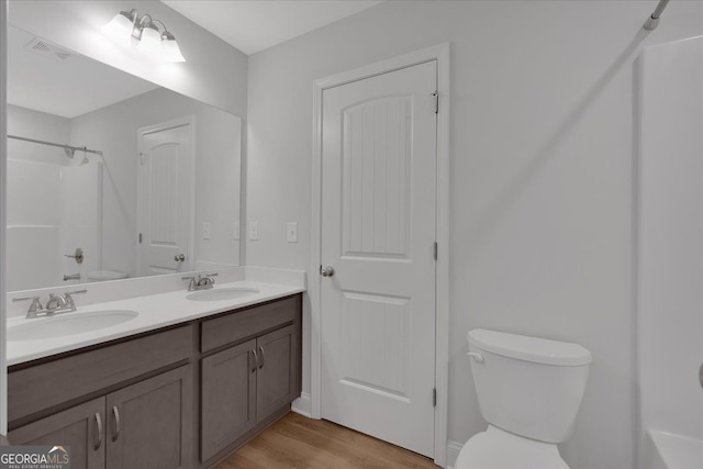 full bath featuring toilet, wood finished floors, and double vanity
