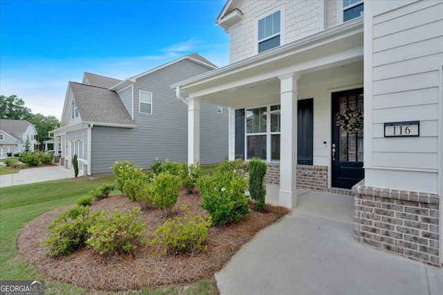 doorway to property featuring a porch and brick siding