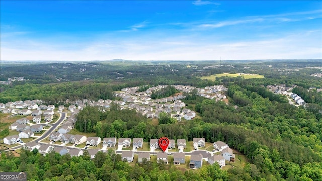 view of property location featuring a forest and nearby suburban area