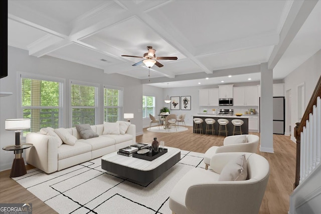 living room featuring ceiling fan, coffered ceiling, beamed ceiling, baseboards, and light wood finished floors