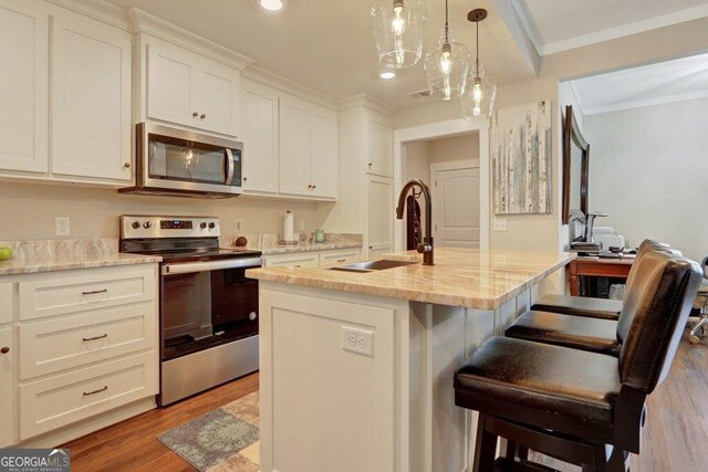 233 Isabella Way, Jesup, GA 31546 - kitchen featuring appliances with stainless steel finishes, a sink, wood finished floors, ornamental molding, and a kitchen breakfast bar