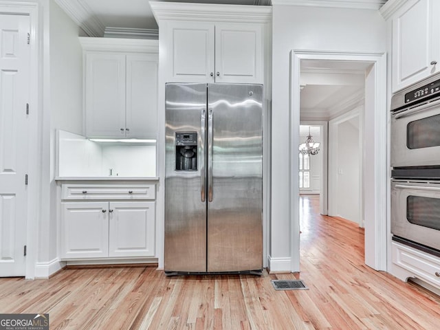 414 Candler Trl, Canton, GA 30115 - kitchen with appliances with stainless steel finishes, crown molding, a chandelier, white cabinets, and light wood-type flooring