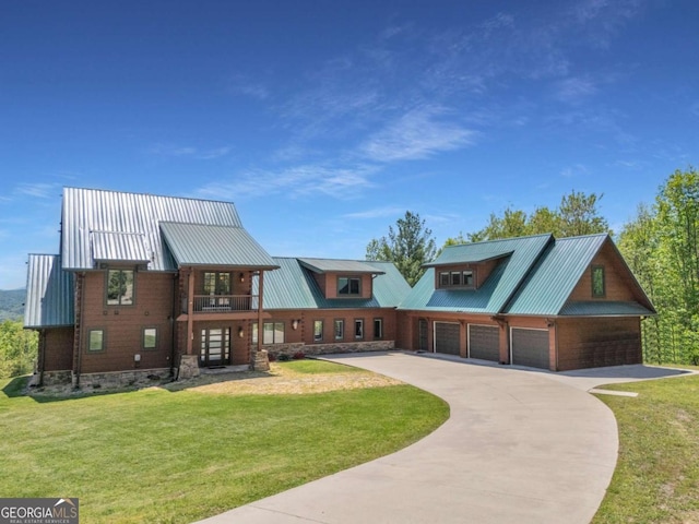 view of front of house with a front lawn, a detached garage, metal roof, and driveway