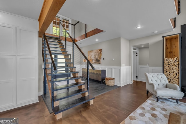 staircase featuring a wainscoted wall, recessed lighting, wood finished floors, and a decorative wall