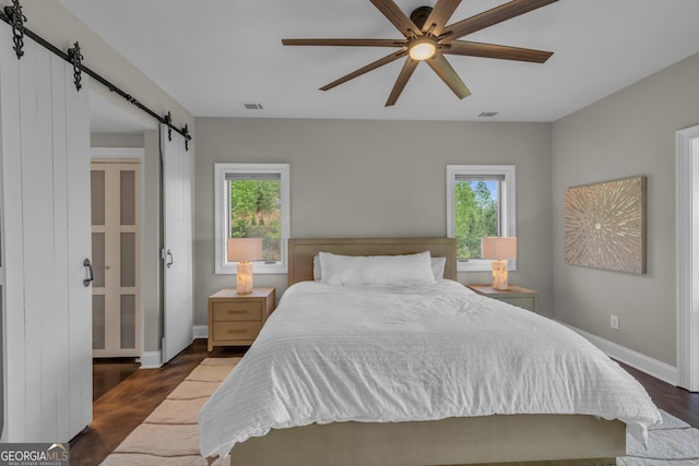 bedroom featuring multiple windows, a barn door, and dark wood-type flooring