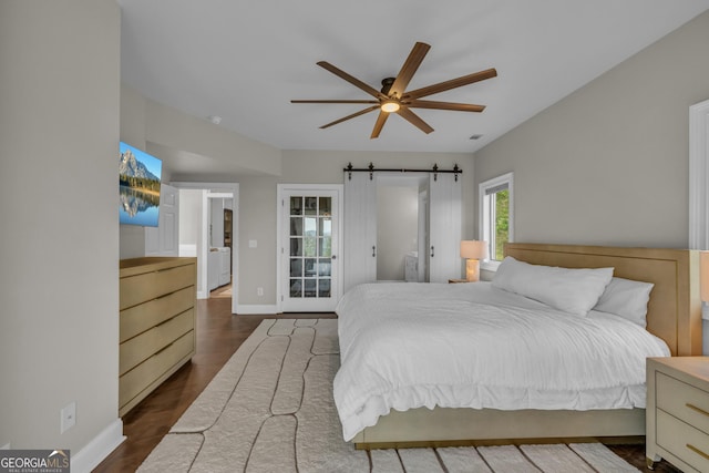 bedroom with baseboards, a barn door, dark wood-type flooring, and access to exterior