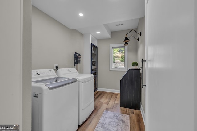 clothes washing area with washing machine and dryer, light wood-style floors, baseboards, and recessed lighting