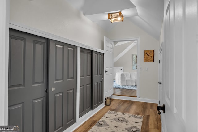 hallway with vaulted ceiling and light wood-style floors