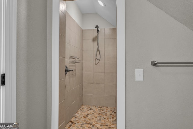 bathroom featuring tiled shower and a textured wall
