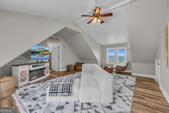 bedroom with wood finished floors, vaulted ceiling, baseboards, and a ceiling fan