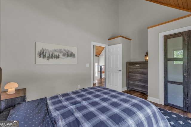 bedroom with wood finished floors, baseboards, wine cooler, and high vaulted ceiling