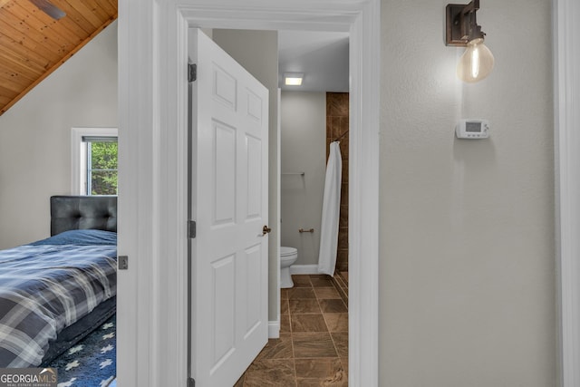 corridor with vaulted ceiling, baseboards, dark stone finish flooring, and wooden ceiling