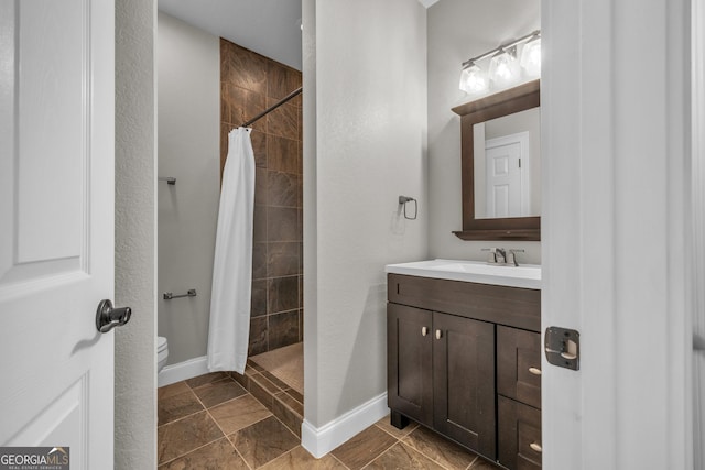 full bathroom featuring tiled shower, toilet, baseboards, and vanity