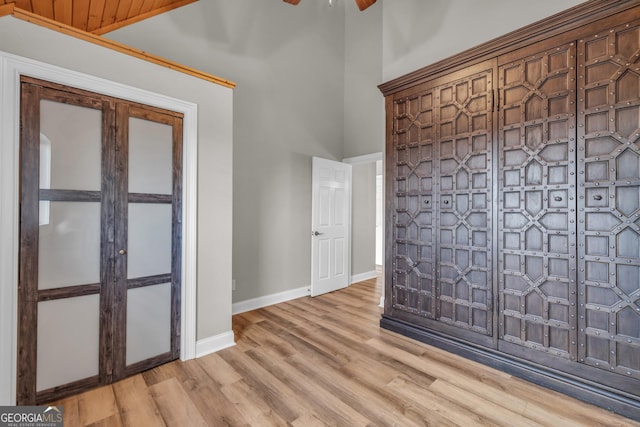 unfurnished room with a ceiling fan, wood finished floors, baseboards, and a towering ceiling