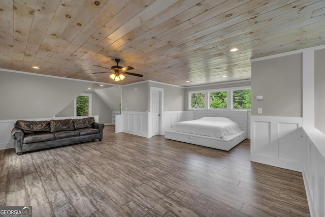 bedroom with multiple windows, a wainscoted wall, wooden ceiling, crown molding, and wood finished floors