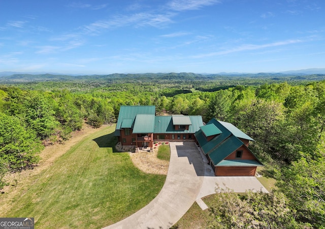 view of subject property with a heavily wooded area and a mountain backdrop