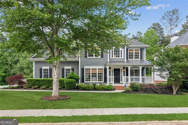view of front of property featuring a porch, a front yard, and a standing seam roof