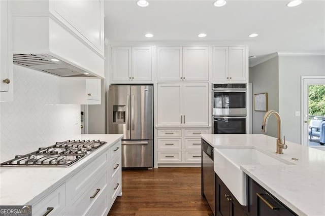kitchen featuring stainless steel appliances, a sink, white cabinetry, ornamental molding, and tasteful backsplash