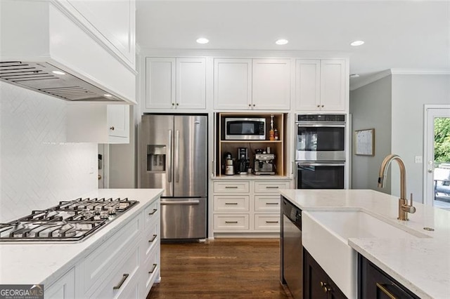 kitchen with stainless steel appliances, custom exhaust hood, a sink, ornamental molding, and light stone counters
