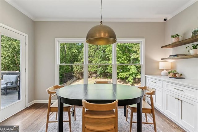 dining room with light wood-style floors, ornamental molding, and baseboards