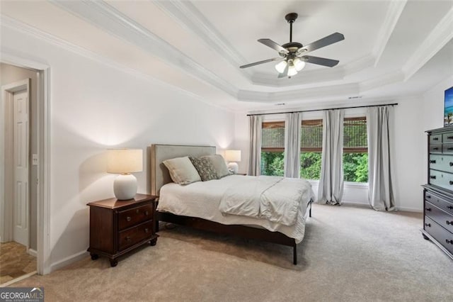 bedroom with light carpet, a tray ceiling, ornamental molding, baseboards, and a ceiling fan