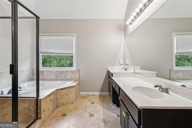 bathroom featuring double vanity, a garden tub, and baseboards