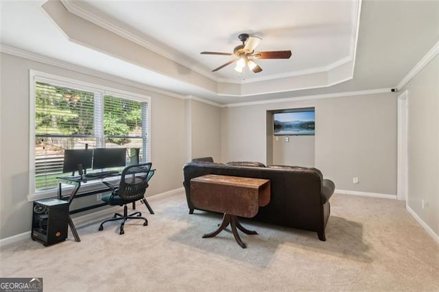 carpeted home office featuring a tray ceiling, crown molding, ceiling fan, and baseboards
