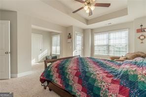 bedroom with a raised ceiling, carpet, baseboards, and a ceiling fan