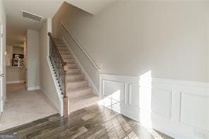 additional living space featuring a decorative wall, stairs, a wainscoted wall, and wood finished floors