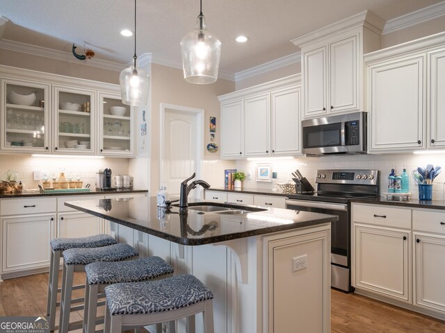 137 Ryan Nicholas Dr, Kingsland, GA 31548 - kitchen with appliances with stainless steel finishes, a sink, backsplash, a breakfast bar, and ornamental molding