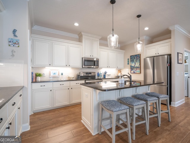 137 Ryan Nicholas Dr, Kingsland, GA 31548 - kitchen with stainless steel appliances, a sink, a kitchen bar, decorative backsplash, and crown molding