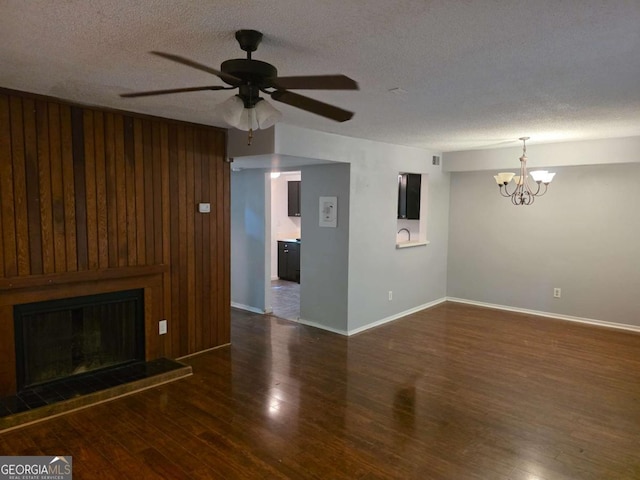unfurnished living room featuring wood finished floors, a textured ceiling, ceiling fan, a chandelier, and baseboards