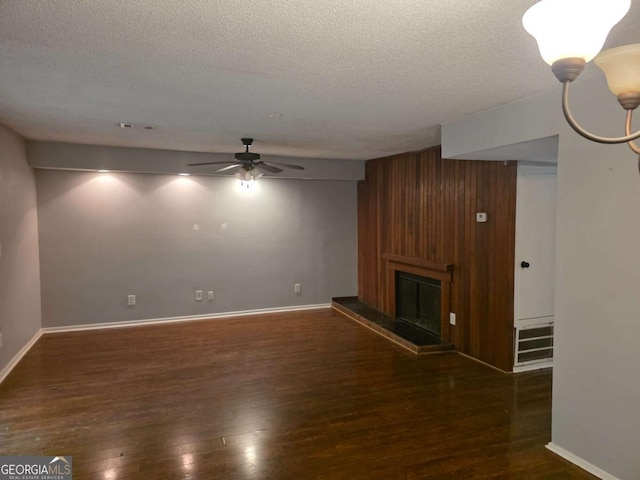 unfurnished living room with wood finished floors, a textured ceiling, a ceiling fan, a large fireplace, and baseboards