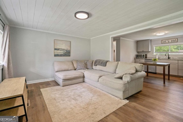 living area with ornamental molding, dark wood-style floors, wooden ceiling, and baseboards