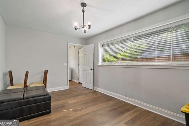 unfurnished room featuring a chandelier, baseboards, and wood finished floors
