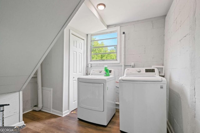 washroom with washer and dryer, dark wood-type flooring, and concrete block wall