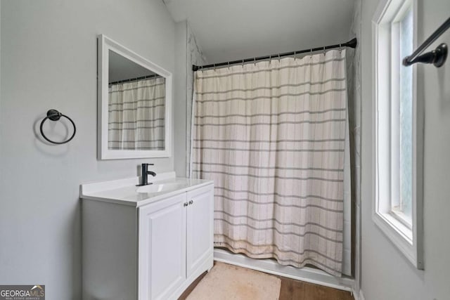 full bath featuring vanity, healthy amount of natural light, shower / bath combination with curtain, and wood finished floors