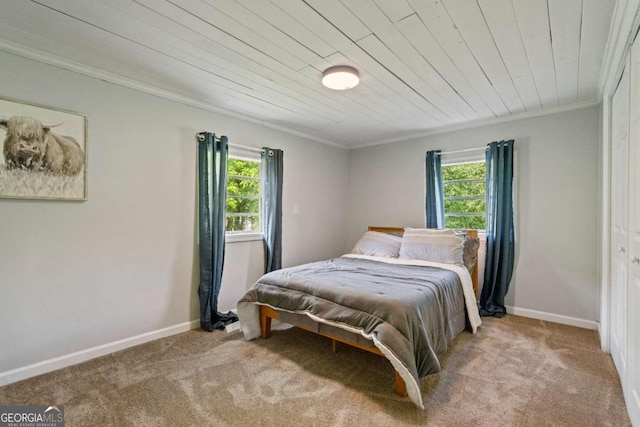 carpeted bedroom with crown molding, baseboards, and wood ceiling