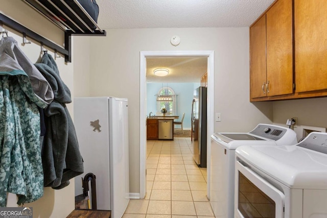 836 Palmetto Tyrone Rd, Sharpsburg, GA 30277 - clothes washing area with washer and clothes dryer, cabinet space, light tile patterned flooring, a textured ceiling, and baseboards