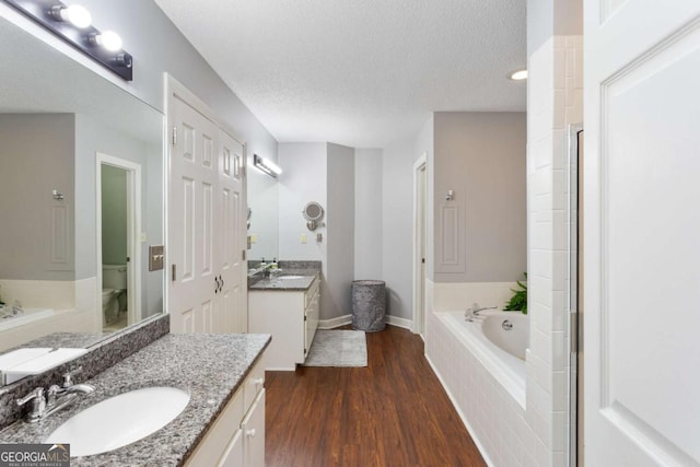836 Palmetto Tyrone Rd, Sharpsburg, GA 30277 - full bathroom featuring a garden tub, two vanities, wood finished floors, toilet, and a textured ceiling