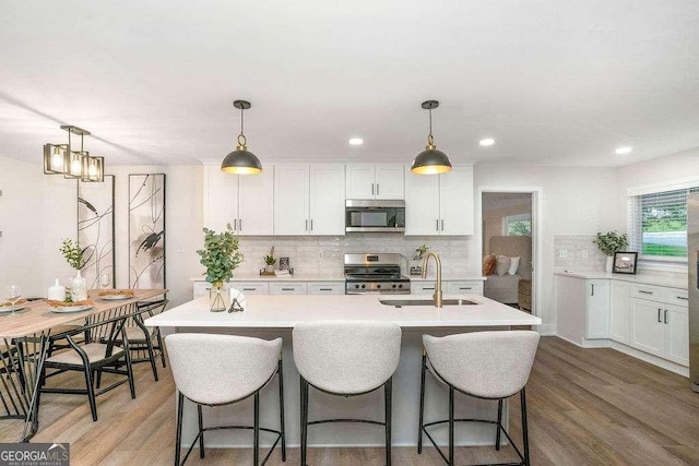 kitchen featuring stainless steel appliances, a sink, decorative backsplash, light countertops, and recessed lighting