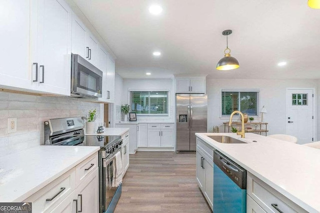 kitchen with stainless steel appliances, a sink, light countertops, white cabinets, and recessed lighting