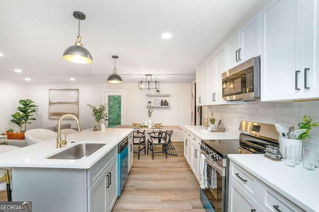 kitchen featuring appliances with stainless steel finishes, a sink, light countertops, white cabinets, and recessed lighting