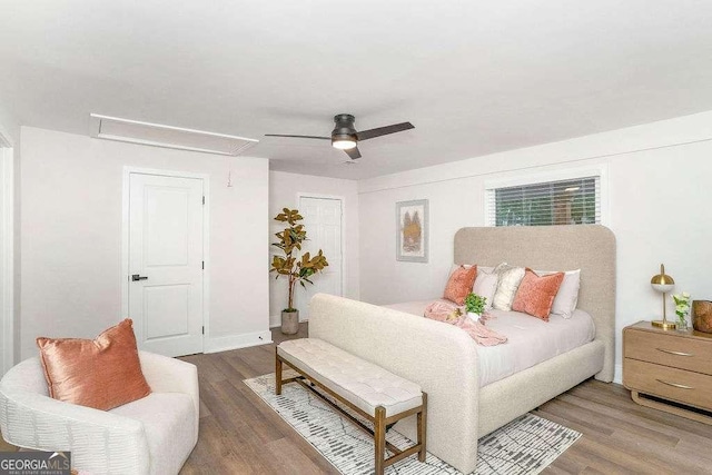 bedroom with attic access, wood finished floors, and a ceiling fan