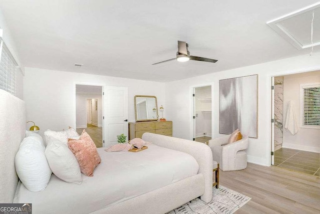 bedroom featuring attic access, light wood-type flooring, baseboards, and connected bathroom