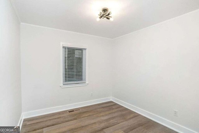 empty room featuring ornamental molding, dark wood finished floors, and baseboards