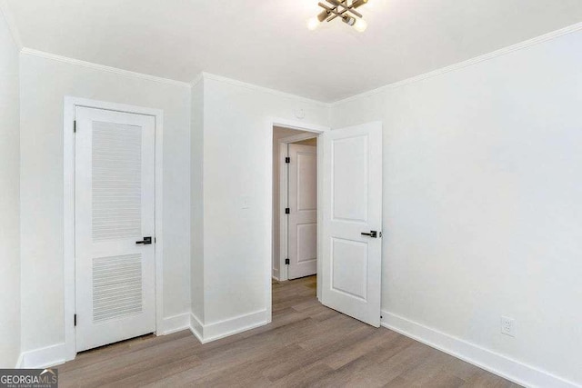 unfurnished bedroom with wood finished floors, baseboards, and ornamental molding