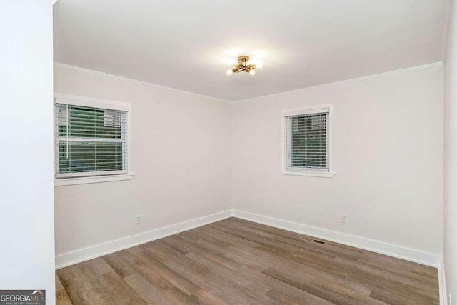 spare room featuring ornamental molding, wood finished floors, and baseboards
