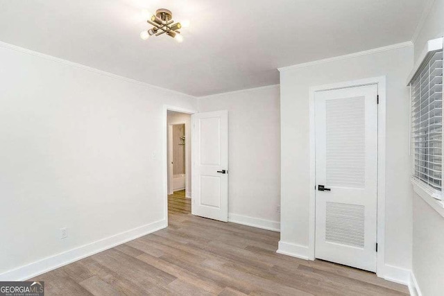 unfurnished bedroom featuring wood finished floors, crown molding, and baseboards